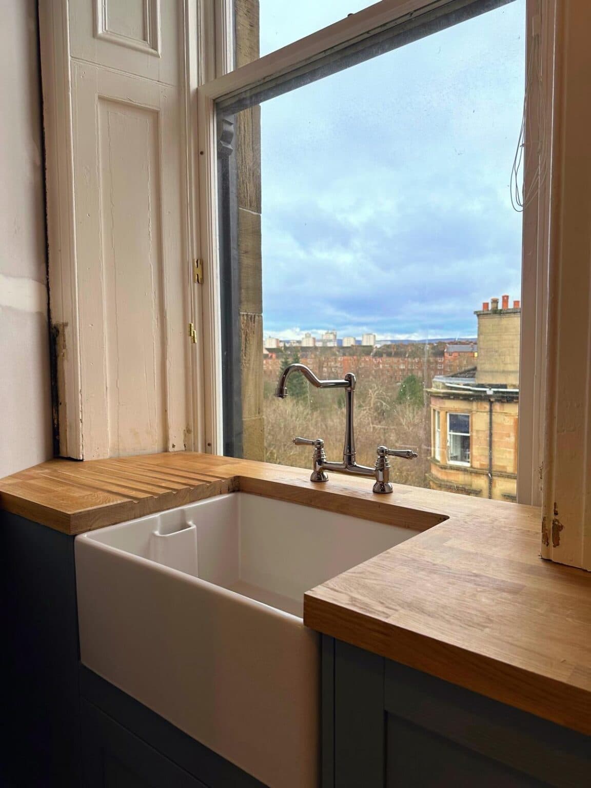 Oak worktop with a drainer and butler sink fitted under a sash window