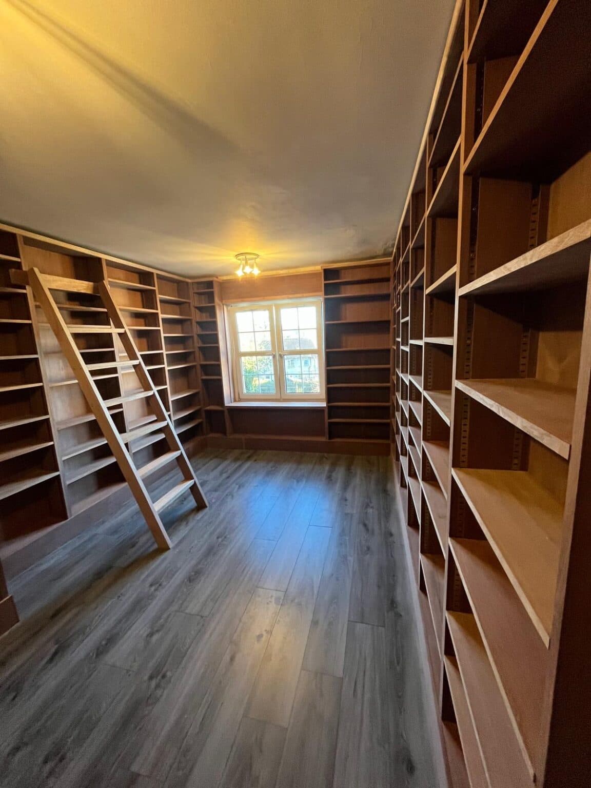 Wall-to-wall library shelving in timber, with a rolling ladder